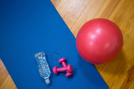 适合性球 水瓶 哑铃和木地板上的运动垫图片