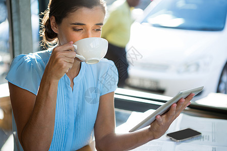 女性执行官在喝咖啡时使用数字平板电脑图片