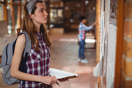 走廊上的女学生阅读通知栏板女孩知识智力女性服装青春期友谊公告栏闲暇教育图片