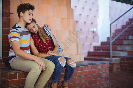 坐在台阶旁边的一对不安的学校夫妇同学童年男生孩子智力友谊服装拥抱女性安慰图片