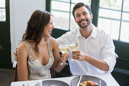 快乐的一对烤面包红酒杯女士服装桌子酒店酒精男人微笑休闲男性食物图片