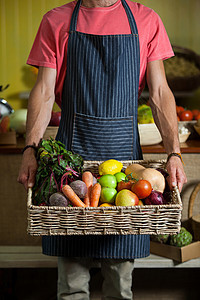 男性工作人员中间科 在有机科把新鲜蔬菜放进篮子中生产健康饮食男人店铺水果耐力围裙零售服务挑战图片