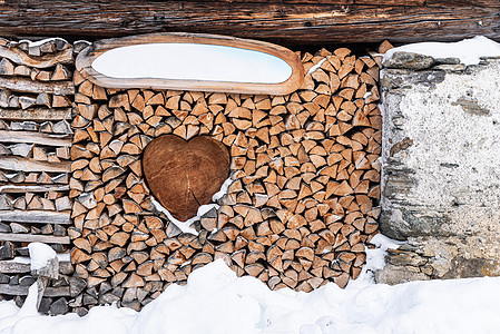 壁炉的木头以艺术的方式排列 中间有一颗木心 周围有雪的冬天风景图片