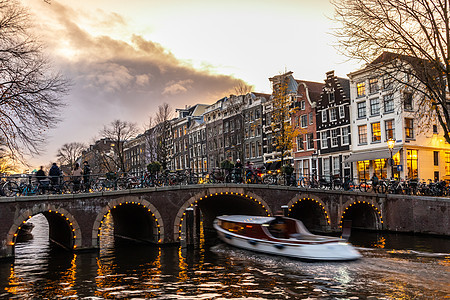 阿姆斯特丹市在黄昏的宁静景象很美 沿街和运河桥上骑自行车房子特丹文化房屋首都反射建筑学运动街道橙子图片
