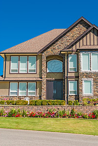 豪华家庭房子 前院有鲜花 在蓝天背景的蓝天背景上图片