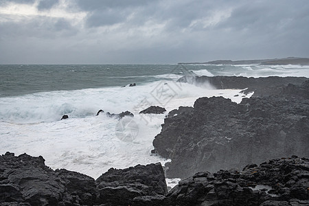 冰岛暴风波冲击黑玄武岩的风暴浪 其间是冰河中布利姆克蒂尔熔岩岩池图片