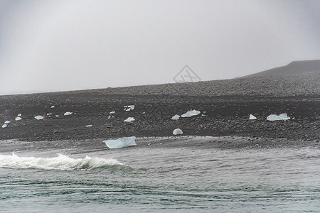 钻石海滩黑沙滩 黑色沙子晶状结晶 一块清澈的冰块被冲上岸边图片