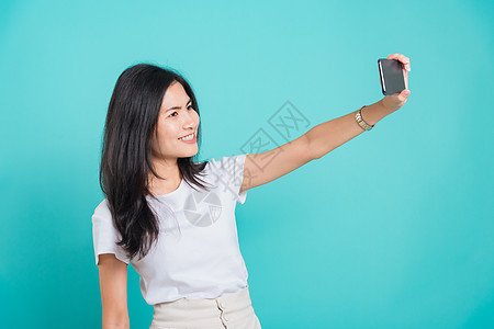 年轻女人站着自拍技术摄影工作室照片蓝色视频电话手机乐趣女孩背景图片