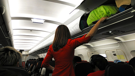 行李载货游客女士飞机女性乘客职员女孩高架储物柜帮助图片