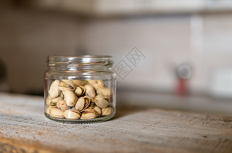 开心果放在一个罐子里 放在一张白色的老式桌子上 背景是厨房 开心果是一种健康的素食蛋白质营养食品 在土气老木头的开心果盐渍核心宏图片