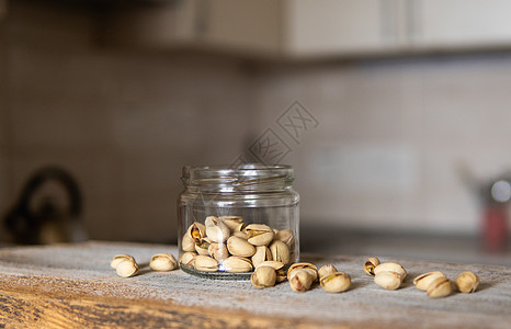 开心果装在罐子里 开心果散落在罐子周围 罐子放在白色复古桌上 背景是厨房 开心果是一种健康的素食蛋白质营养食品木头榛子种子坚果水图片