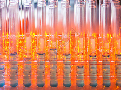 在暖橙色背景上装有蓝色液体的玻璃试管化学家临床样本生物实验室管子器皿化学品烧杯解决方案图片