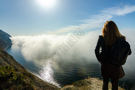 女孩正从山上观望着一个海景异常的奇异海景 海云笼罩着大海背景图片