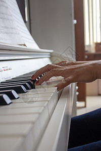 妇女用她的白色电动钢琴在练习课程学习旋律音乐会纽扣笔记手指艺术家音乐歌曲玩家图片