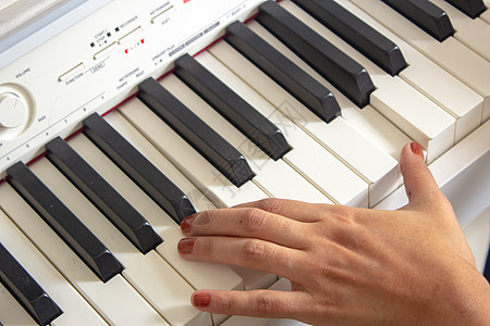 妇女用她的白色电动钢琴在练习课程纽扣钢琴家笔记音乐会艺术玩家乐器手指学习钥匙图片