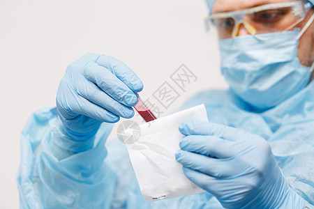 特写医生手拿着血样 医用器材 验血 一名医生佩戴个人防护设备 包括面罩 护目镜和防护服 以保护 COVID19 冠状病毒感染实验图片