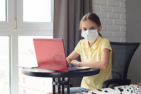 生病的女童坐在一张桌子上 在网上学习 对框架进行考察图片