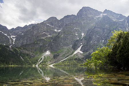 美丽的夏日高山湖景覆盖着绿树和天空中的阳光 山在水中的倒影 水晶般清澈的水 欧洲 阿尔卑斯山荒野艺术国家山脉池塘叶子蓝色风景顶峰图片