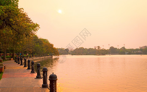 夏天傍晚的湖边公园 日落阳光照亮的花园小径公园车道 风景场景中的红色和橙色 夕阳西下 Dhakuria 湖镇 加尔各答 西孟加拉图片