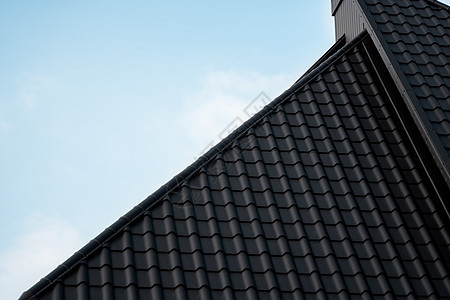 黑色金属瓦屋顶 屋顶金属板 现代类型的屋顶材料 屋瓦的屋顶映衬着蓝天 建筑工作建筑学建造窗户阳光蓝色房子控制板阁楼角落图片