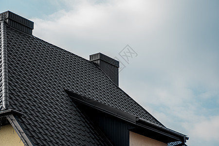 黑色金属瓦屋顶 屋顶金属板 现代类型的屋顶材料 屋瓦的屋顶映衬着蓝天 建筑天空床单维修阁楼工作房子建造蓝色控制板窗户图片