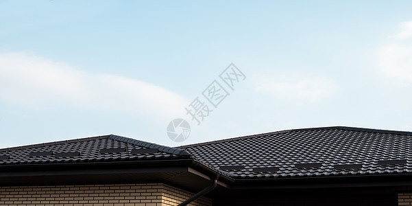 棕色金属瓦屋顶 屋顶金属板 现代类型的屋顶材料 屋瓦的屋顶映衬着蓝天 建筑工作房子窗户天空床单建造控制板蓝色建筑学阁楼图片