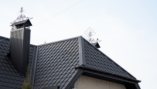 黑色金属瓦屋顶 屋顶金属板 现代类型的屋顶材料 屋瓦的屋顶映衬着蓝天 建筑窗户房子床单阁楼角落阳光蓝色天空建筑学工作图片