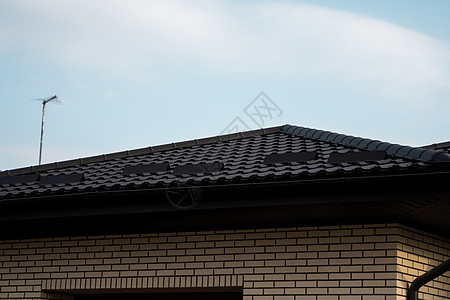 棕色金属瓦屋顶 屋顶金属板 现代类型的屋顶材料 屋瓦的屋顶映衬着蓝天 建筑维修天空窗户阁楼建筑学控制板房子蓝色角落床单图片