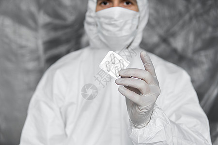 身穿白色防护服 医用口罩和橡胶手套的医生拿着白色药丸作为治疗冠状病毒大流行威胁的药物 冠状病毒covid 19的流行病 流行病消图片