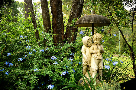 花园里一对年轻夫妇的雕像 手持雨伞高清图片