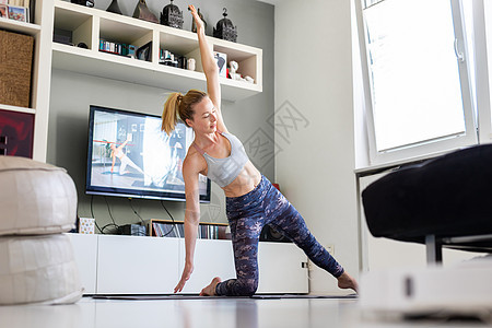 有魅力的运动女性在家锻炼 在客厅的电视机前做普拉提运动 社交隔离 在冠状病毒大流行期间保持健康并待在家里活力地面程序沉思瑜伽腹肌图片