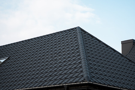 黑色金属瓦屋顶 屋顶金属板 现代类型的屋顶材料 屋瓦的屋顶映衬着蓝天 建筑角落阳光窗户房子阁楼工作床单维修建造控制板图片