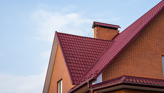 红色金属瓦屋顶 屋顶金属板 现代类型的屋顶材料 屋瓦的屋顶映衬着蓝天 建筑图片