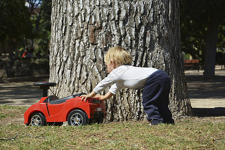 金发男孩玩他的红色玩具车图片
