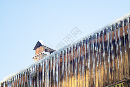 木屋顶的冰柱天空房子冻结危险水晶木头天气太阳蓝色季节图片