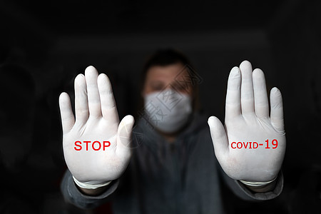 戴医疗面具和手套的男子用两只手展示了STOP 红色文字在黑暗背景上停止COVID 19 科罗纳病毒感染保护概念图片