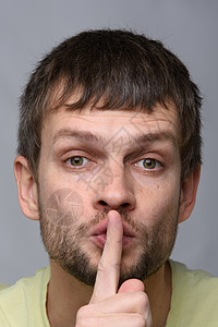 一个欧洲外貌的人的肖像 他用手指指着嘴 沉默的手势 密闭图片