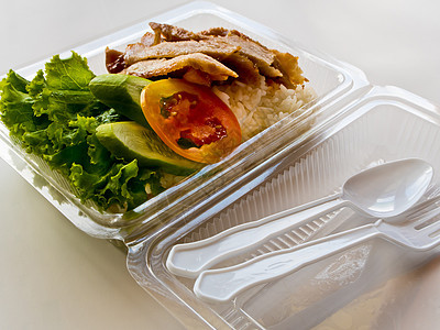 在塑料箱中烤猪肉和大米白色塑料美食盒子炙烤黄瓜绿色蔬菜午餐包装图片