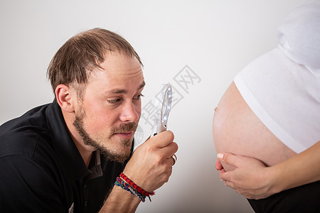 英俊的男人在听着他美丽的怀孕妻子的肚子和笑容女士女性爸爸身体丈夫母性腹部家庭成人孩子图片