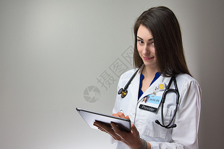 执业护士在平板电脑上做笔记以供患者绘制图表 带听诊器和徽章的女性医护人员在医疗服务提供者环境中使用技术图片