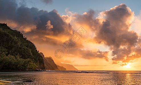 日落在夏威夷Kauai岛纳帕利海岸沉没的山脉上沿海岩石天空海滩假期旅行海岸线阳光悬崖海岸图片