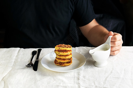 一个穿黑色T恤的割礼男子手里拿着一条白肉汁船 把卷饼倒在一身抹酸奶油酱的普通白桌布上 简单健康早餐 概念餐具餐巾生活方式美食牛奶图片