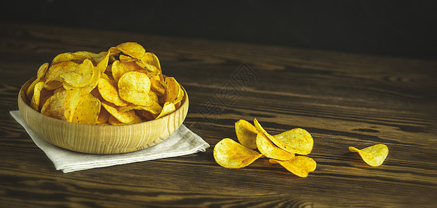 碗里的马铃薯片在木制背景上美食食物土豆垃圾盘子玉米香料油炸营养育肥图片