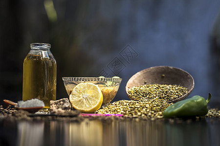 特写玻璃碗中的绿豆汤及其所有成分 包括绿豆 绿豆 阿魏 小茴香 绿辣椒 黑胡椒粒 柠檬汁和黑色表面的盐热带美食柠檬汁扁豆香料国家图片