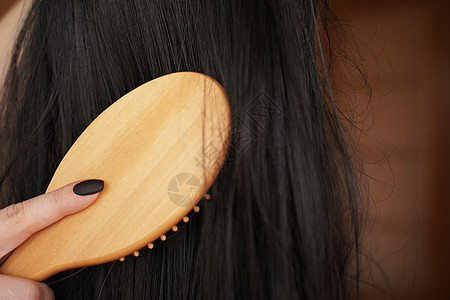 女性手握黑假发 长头发 梳木梳子卷曲按摩女士模型沙龙幸福发型工作室理发人体图片