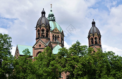 慕尼黑圣卢克教堂的塔和穹顶在树后面图片