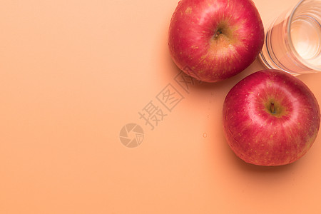 红苹果和杯子水 在橙色背景上隔绝 Hea图片