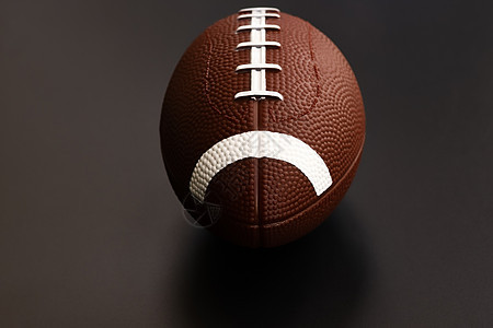 孤立在黑色背景上的美式足球 运动对象 c猪皮皮革场地橄榄球硬木比赛娱乐阴影接缝聚光灯图片