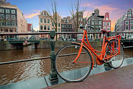沿荷兰阿姆斯特丹运河的橙色骑自行车旅游城市运输街道世界遗产历史性天际游客路面历史图片