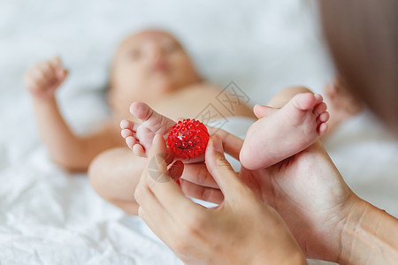 母亲握着新生婴儿的脚 小手指和红按摩舞会在女人手中 在家很舒适压痛白色红色童年儿子父母脚趾母性男生妈妈图片